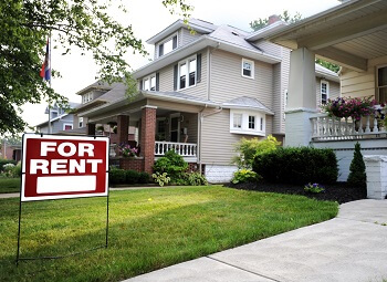 Red for rent sign in the front yard of a single family home